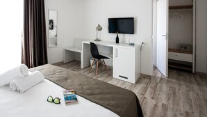 Habitación de hotel con cama, escritorio, silla, televisión y armario.