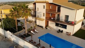 Un edificio moderno de dos pisos con piscina, balcones y un jardín.