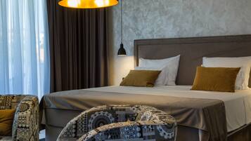 A hotel room with a large bed, a patterned armchair, and a modern pendant light.