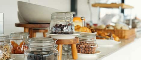 A breakfast buffet with various food items in glass jars and bowls, including nuts and pastries.