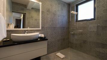 Un baño moderno con un espejo grande, un lavamanos y una zona de ducha.