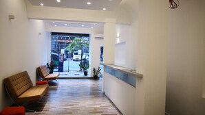 A modern reception area with a wooden floor, a reception desk, and seating area with benches. - The Capsule Hotel (Colombo)