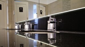 A modern bathroom with a black countertop, chrome fixtures, and a glass partition. - The Capsule Hotel (Colombo)