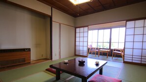 A traditional Japanese room with tatami flooring, a low table with a tea set, and sliding doors leading to a balcony with chairs. - Lake Side Hotel MINATOYA (Inawashiro)