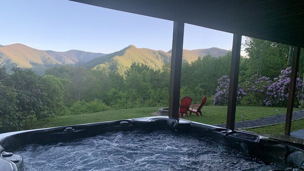 Un bain à remous avec vue sur les montagnes et un jardin agrémenté de chaises.