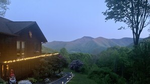 Une maison avec un chemin qui traverse le jardin, entourée de verdure et de montagnes.