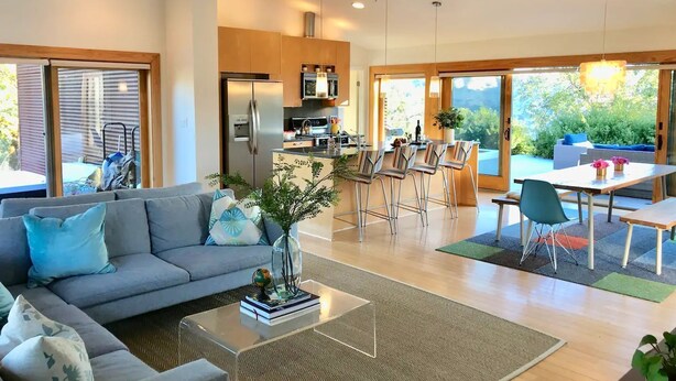 A modern living room with a grey sofa, a coffee table, and a dining area with a table and chairs.