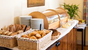 A buffet setup with various breads, plates, and a glass container. - Gutshaus Barkow (Barkhagen)