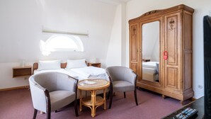 A hotel room with a bed, two armchairs, a small round table, a wooden wardrobe, and a television. - Gutshaus Barkow (Barkhagen)