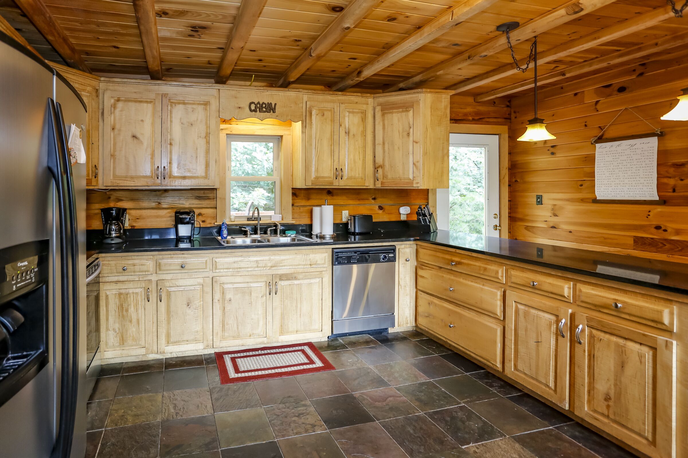 A cabin-style kitchen with wooden cabinets, a stainless steel refrigerator, and a dishwasher.