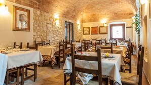 A restaurant with stone walls and brick ceiling, wooden tables, and white tablecloths. - La Locanda di Mariella (Poggio Picenze)