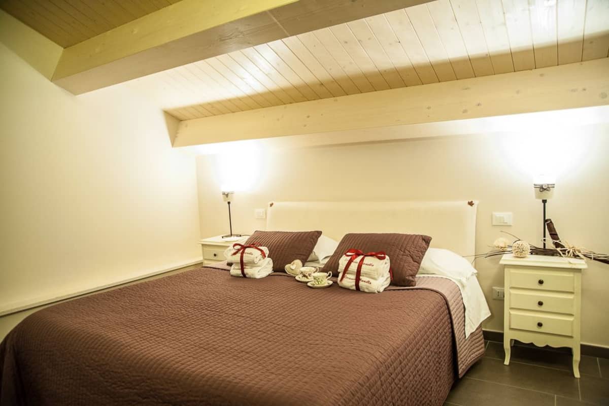 Une chambre d’hôtel avec un lit, des tables de chevet et un plafond avec des poutres en bois.