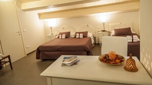 A hotel room with two beds, a small table with a magazine and a fruit platter, and a nightstand with a lamp. - La Locanda di Mariella (Poggio Picenze)