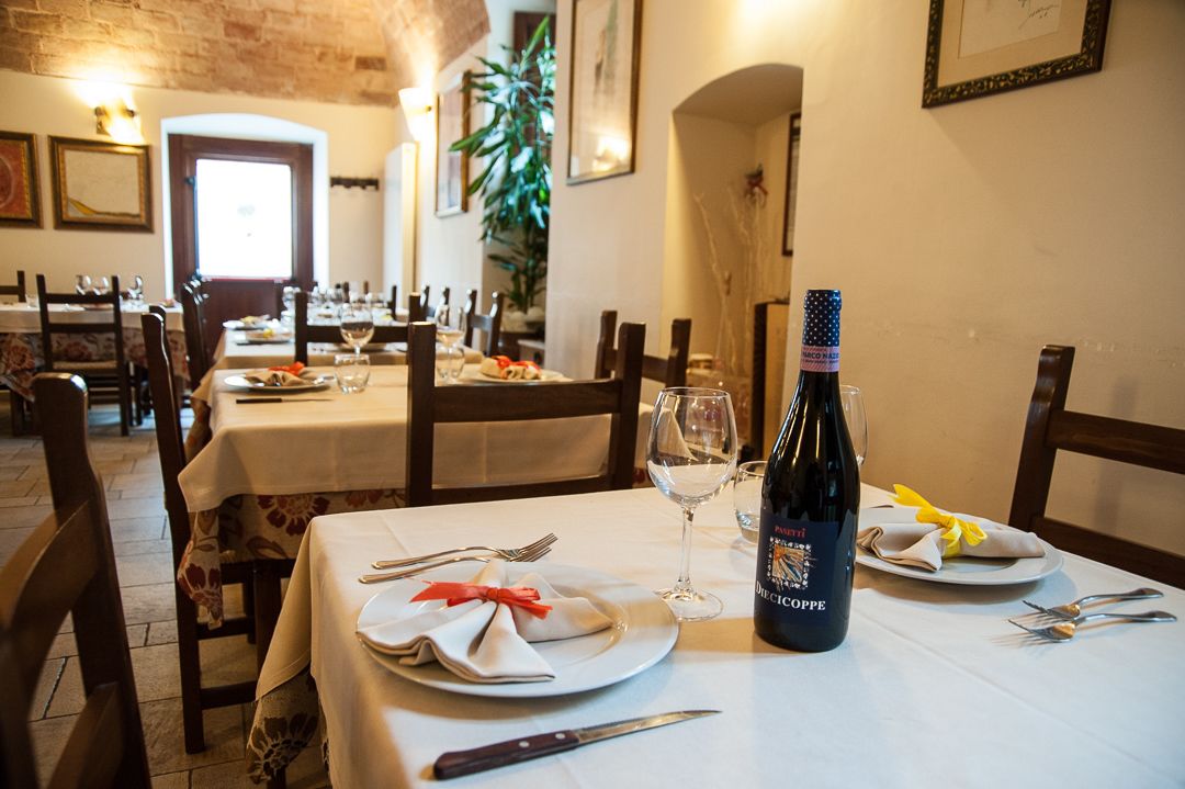 A dining table set with plates, cutlery, and a bottle of wine.