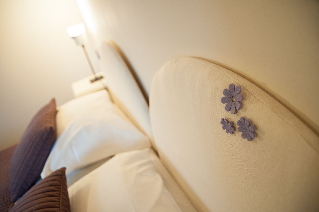 Ein Bett mit Kopfteil, Kissen und dekorativen Blumen.