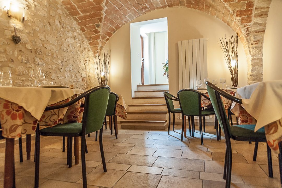 Un coin repas avec des murs en pierre, des chaises vertes et une table dressée pour quatre personnes.