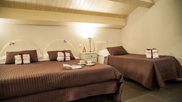 A hotel room with two beds, each with a brown bedspread and pillows, a nightstand with a lamp, and a small table with a teapot and cups.