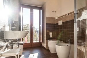 Un baño moderno con un lavamanos grande, dos inodoros y una cabina de ducha de vidrio.