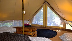 Una tienda de campaña con una cama, un baúl de madera y una ventana que ofrece vistas al exterior.