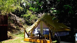 Una carpa con una plataforma de madera, dos sillas y una mesa.
