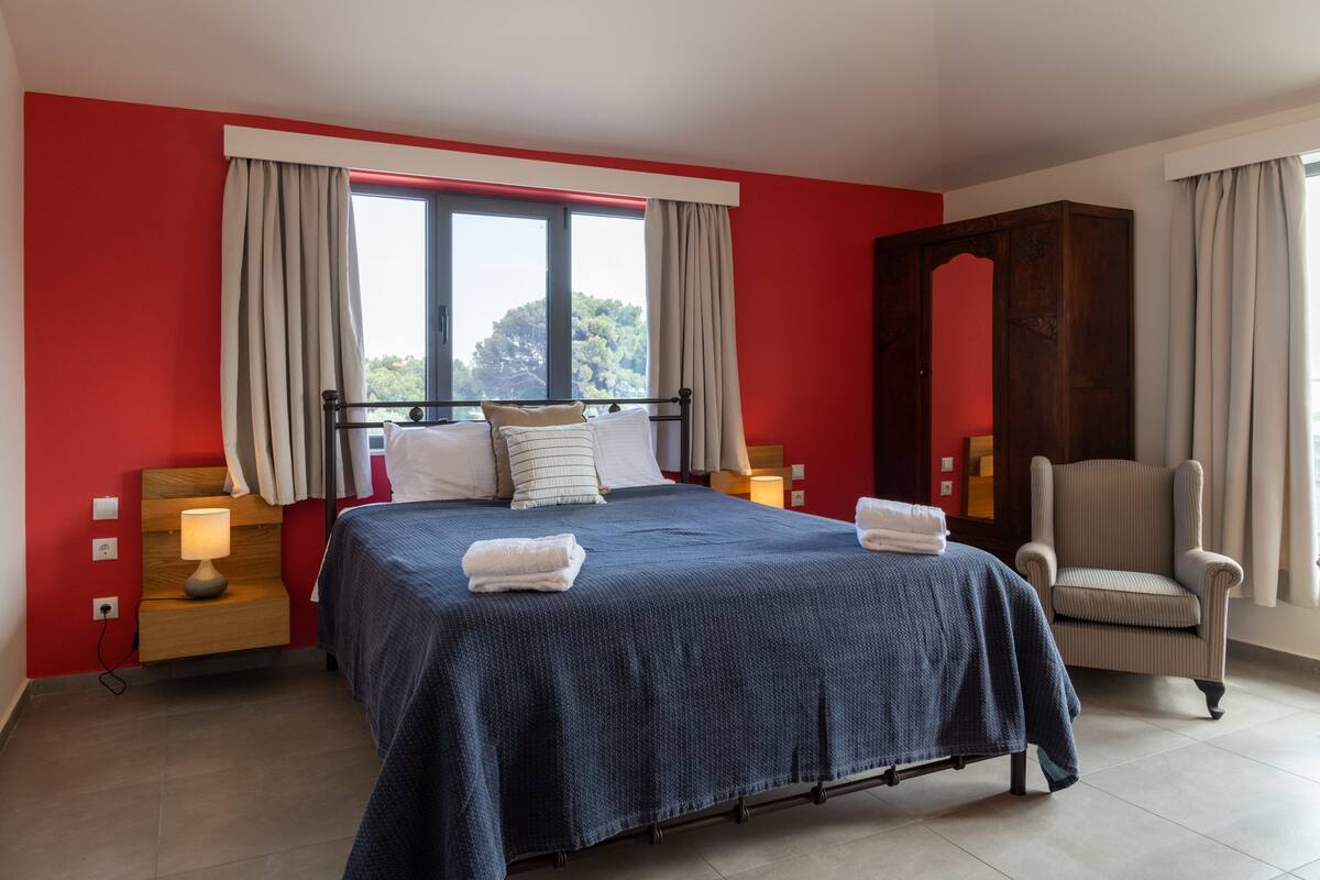 A bedroom with a bed, nightstands, a chair, and a large mirror.