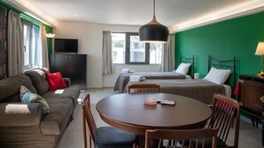A hotel room with a sofa, two single beds, a dining table, and a TV. - CHROMA Lodge Pikermi  (Rafina-Pikermi)