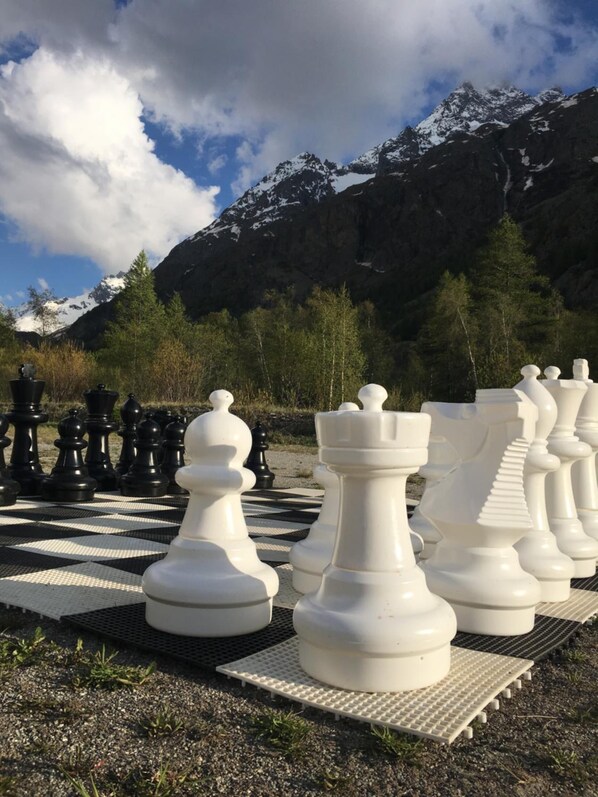 A chessboard set outdoors with large chess pieces, set against a mountainous backdrop. - Le Gîte Le Pas de l'Ane (Villar-d'Arene)
