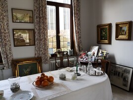 Un comedor con una mesa dispuesta para cuatro, con mantel floreado, un cuenco de naranjas y diferentes copas.