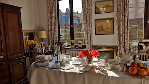A dining table set with plates, cutlery, and a vase of red flowers. - B&B Het Leuvens Hof (Leuven)