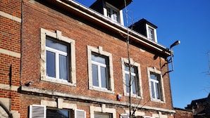A two-story brick building with white shutters, a visible door marked '103', and a small tree in the foreground. - B&B Het Leuvens Hof (Leuven)