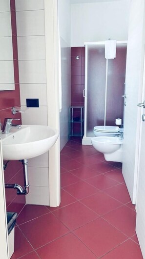 Un baño con lavamanos, inodoro y zona de ducha.