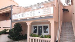 A two-story building with a balcony, a staircase, and a stone-paved entrance. - Apartments Tanja & Josipa (Pag)