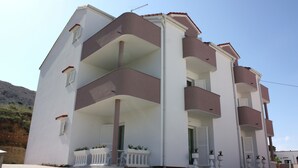A multi-story residential building with balconies, a tiled entrance, and potted plants. - Apartments Tanja & Josipa (Pag)