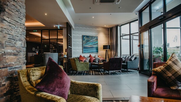 Rebost d'hotel modern amb diferents zones d'aixetes, un gran finestral que ofereix una vista i una paret de maó.