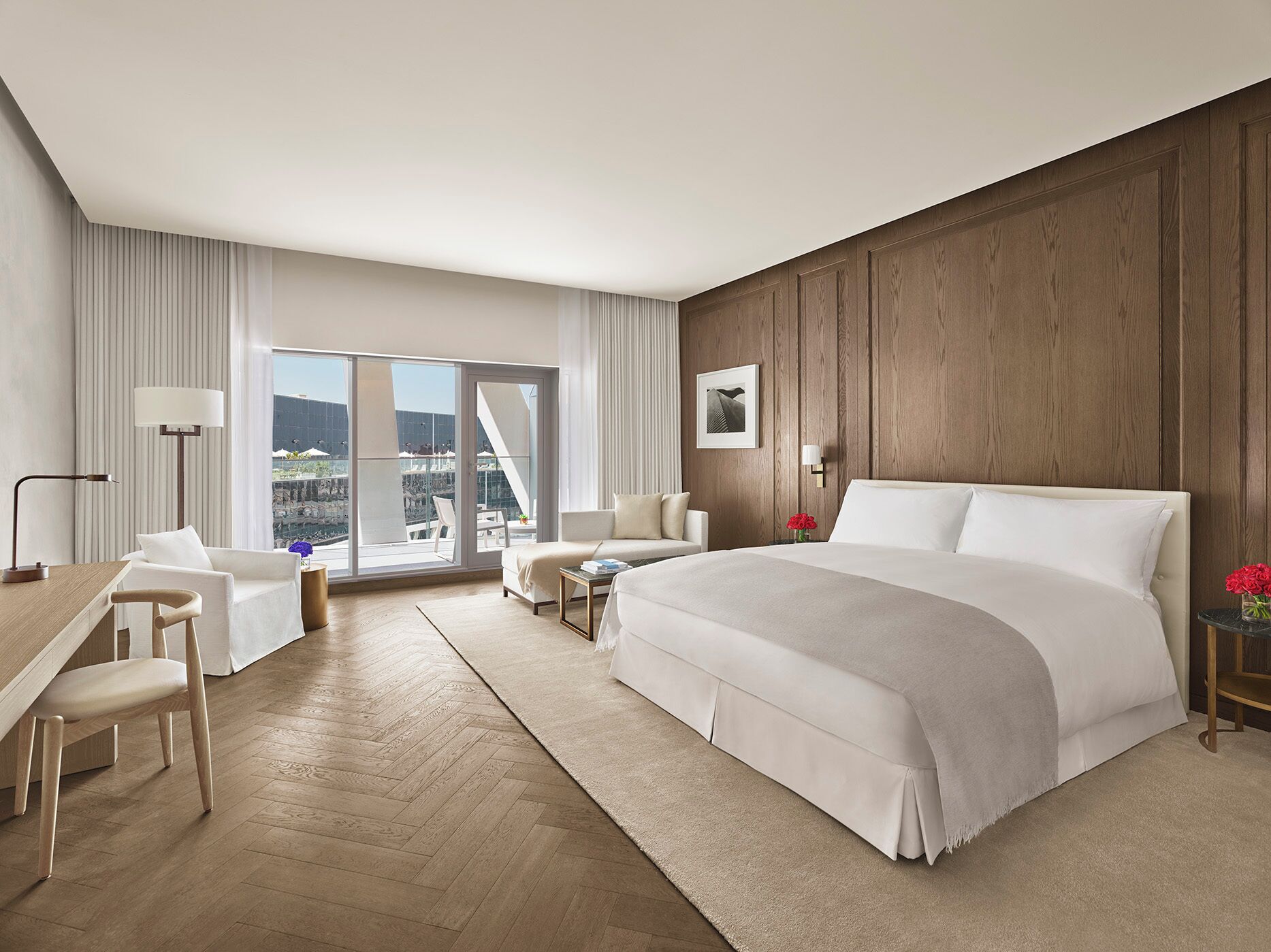 Habitación de hotel con una cama grande, un escritorio, una silla, un sofá y vistas a la ciudad.