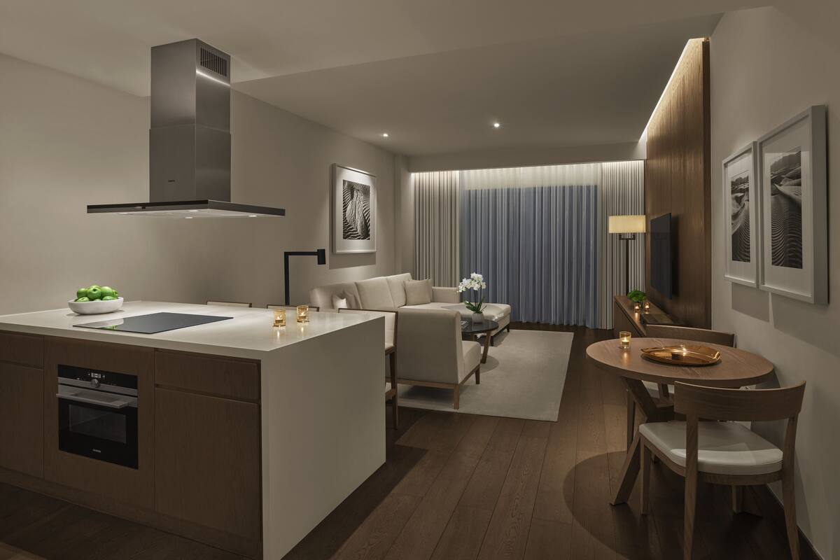 A modern kitchen with a central island, a dining area with a round table, and a living space with a sofa and a TV.