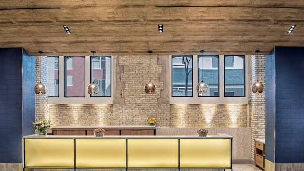 Una cocina moderna con techo de madera, ventanas amplias y una isla central con asientos amarillos.
