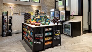 Zona comercial con exhibidores de aperitivos, una sección refrigerada y una caja registradora.