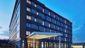 Un hotel moderno con fachada plana, ventanas amplias y un área de acceso cubierta.