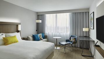Une chambre d’hôtel avec un grand lit, un bureau, une chaise, une petite table et un téléviseur.
