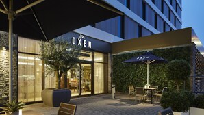 Exterior de un hotel con un letrero que dice "The OXEN", asientos al aire libre y una entrada bien iluminada.