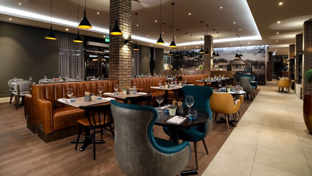 Un restaurante moderno con asientos de cuero, mesas redondas e iluminación colgante.