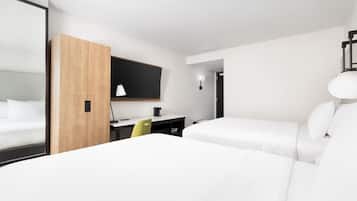 A hotel room with two beds, a desk, a chair, and a mirror.