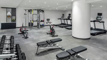 Une salle de sport moderne équipée de tapis de course, de vélos elliptiques et de poids libres.