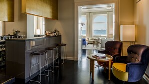 Un moderno espacio de bar con taburetes, una barra y vistas al mar a través de amplios ventanales.