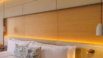 A modern hotel room with a large bed, a wooden headboard, and a bedside lamp.