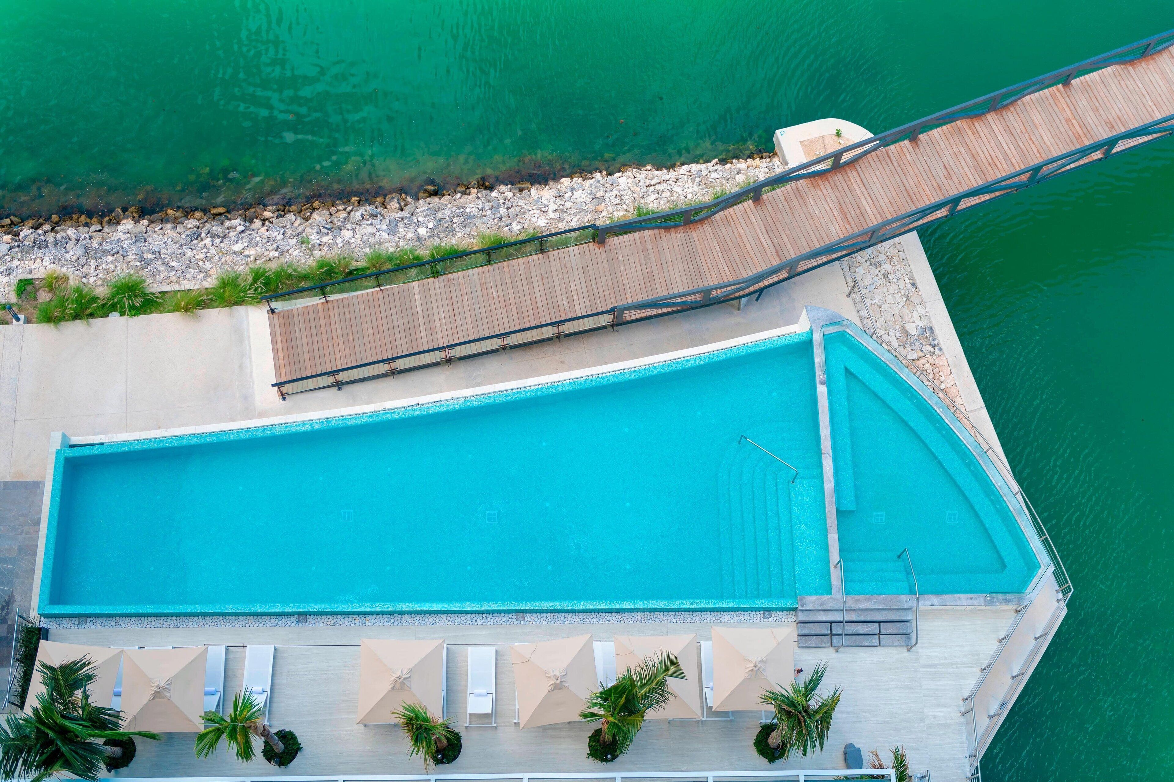 Vista aerea di una piscina con terrazza in legno e poltrona relax.