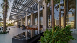 A modern outdoor lounge area with seating, palm trees, and a glass barrier. - Renaissance Cancun Resort & Marina (Cancún)