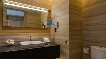 Uma casa de banho moderna com um espelho grande, lavatório e sanita.