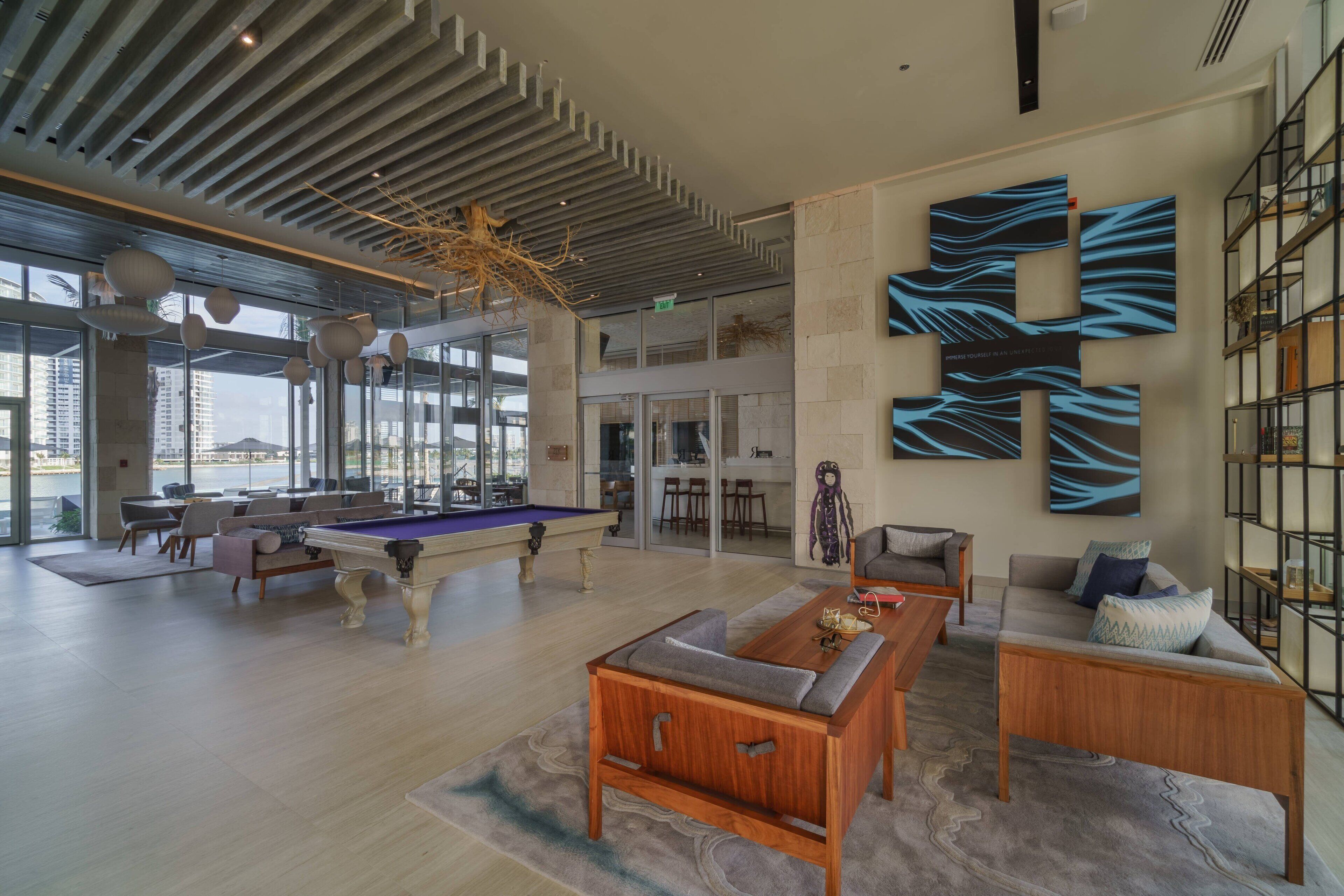 A spacious living area with a pool table, comfortable seating, and a large abstract wall art piece.